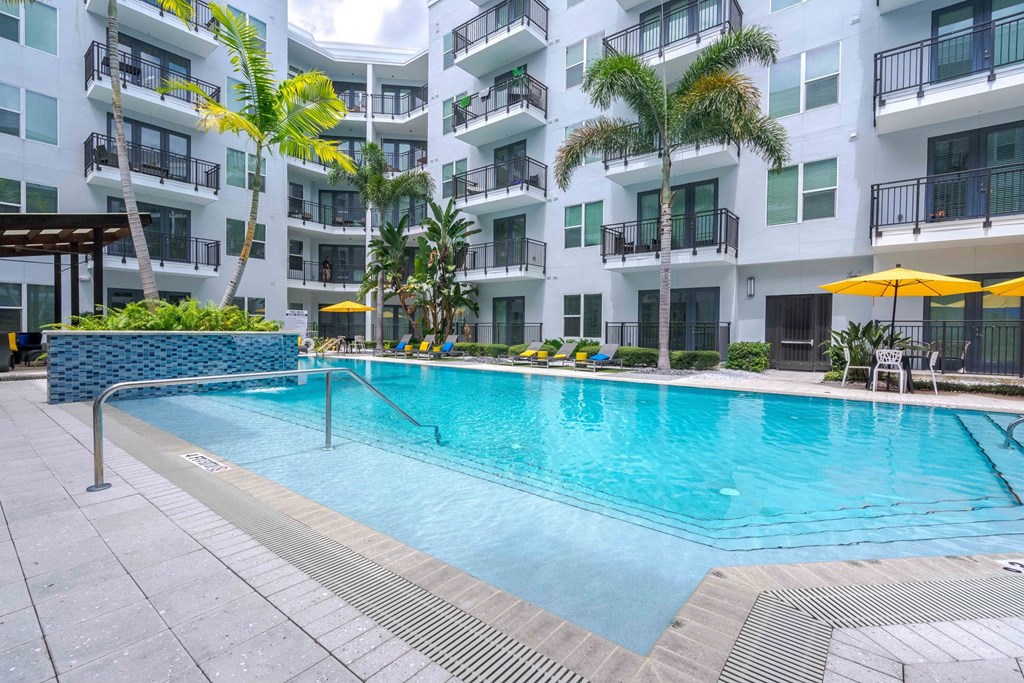 A swimming pool in front of a white building with balconies.