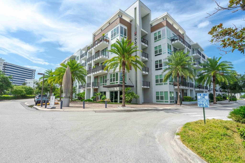 A modern apartment building with a blue sign in front.