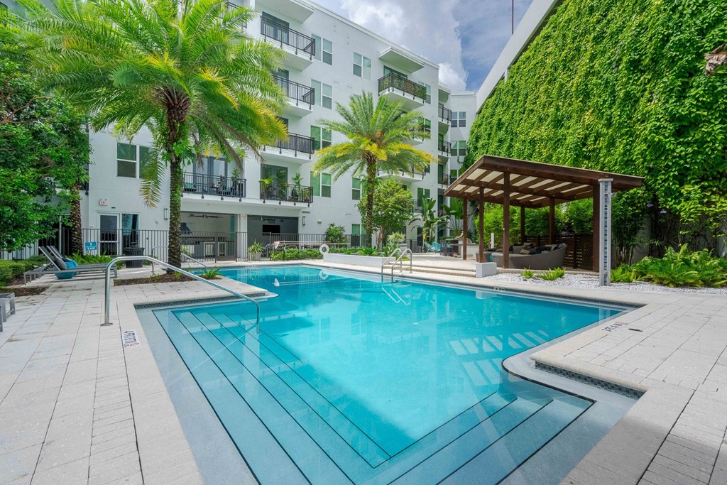 A swimming pool surrounded by a white building and palm trees.