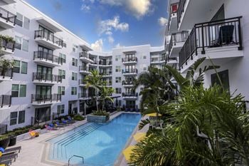 a building with a swimming pool and palm trees in front of it