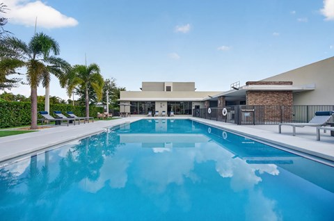 A large swimming pool in front of a building with palm trees in the background.