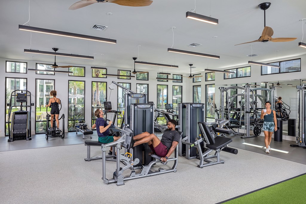 a group of people in a gym with weights and cardio equipment