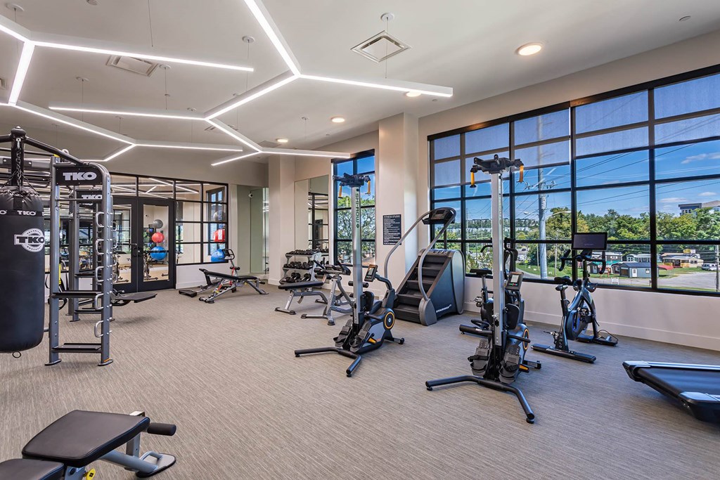 a gym with weights and cardio equipment and large windows
