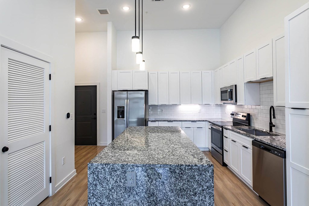 a kitchen with white cabinets and a granite counter top