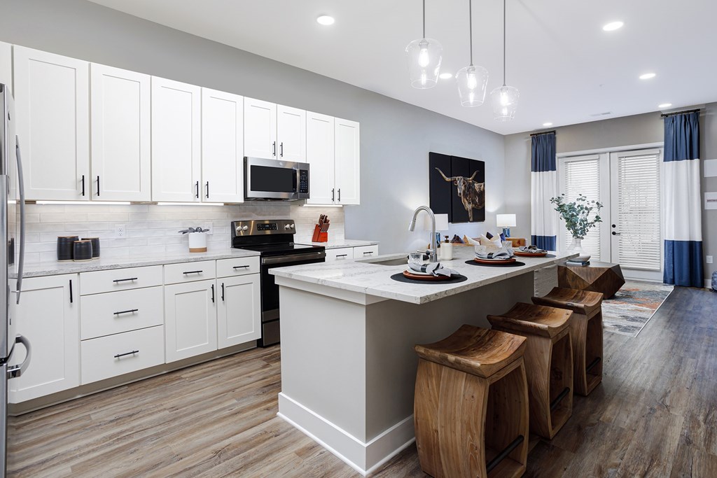 A kitchen with white cabinets and a large island with bar stools.
