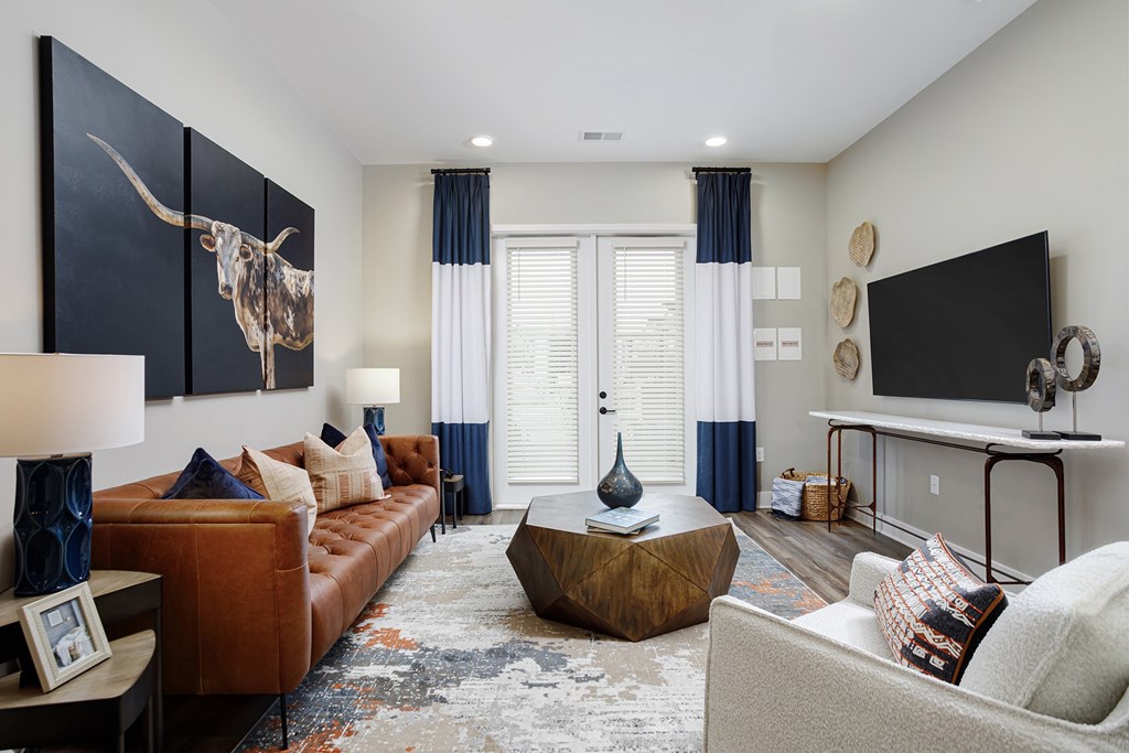 Dog-Friendly Luxury Apartments in West Oakland Park, TN - Vintage Johnson City - A Living Room with a Brown Leather Sofa, Wooden Coffee Table, and Mounted TV.