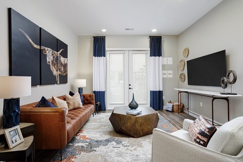 A living room with a brown couch, a coffee table, and a large painting of a bull.