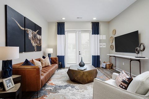 A living room with a brown couch, a coffee table, and a large painting of a bull.