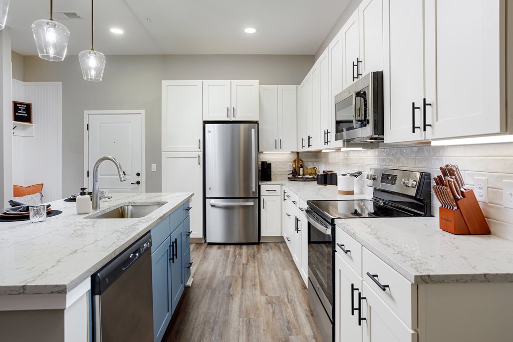 A modern kitchen with a refrigerator, sink, and stove.