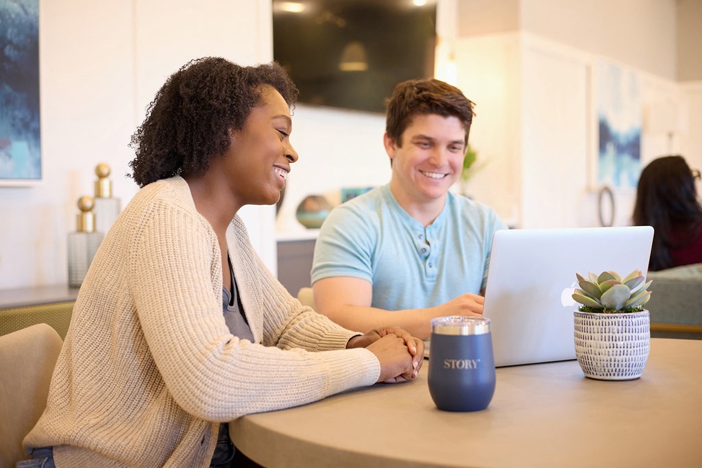 two people sitting at a table with a laptop