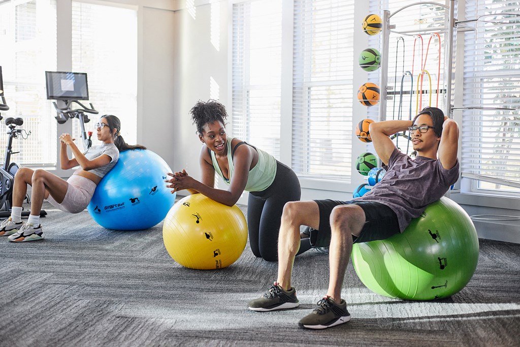 three people sitting on exercise balls in a gym