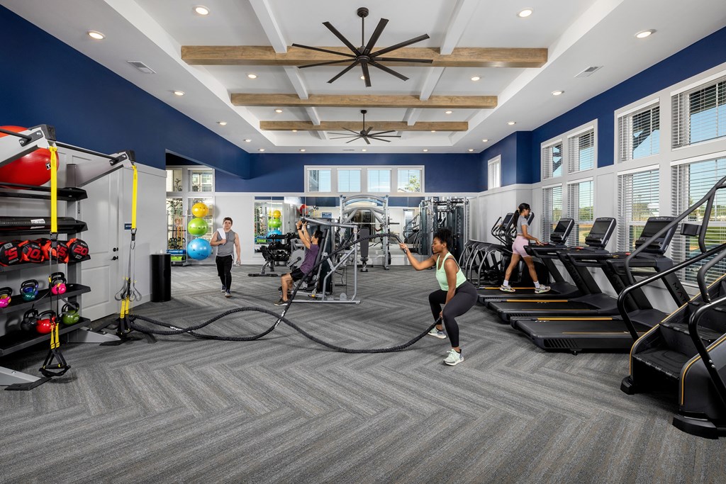a group of people working out in a gym with weights and cardio equipment