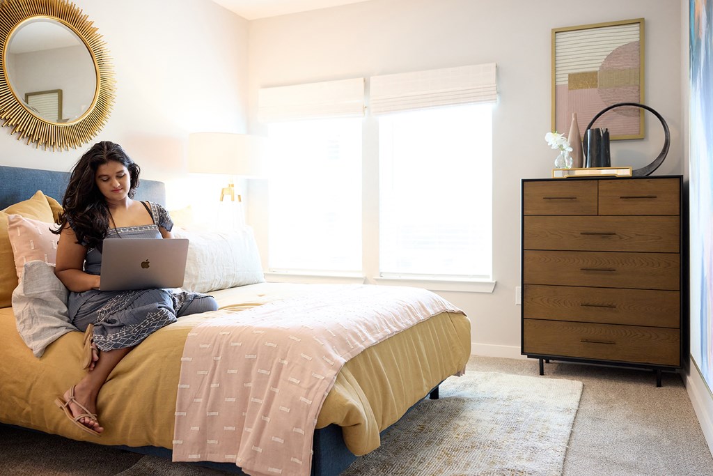 a woman sitting on a bed using a laptop computer