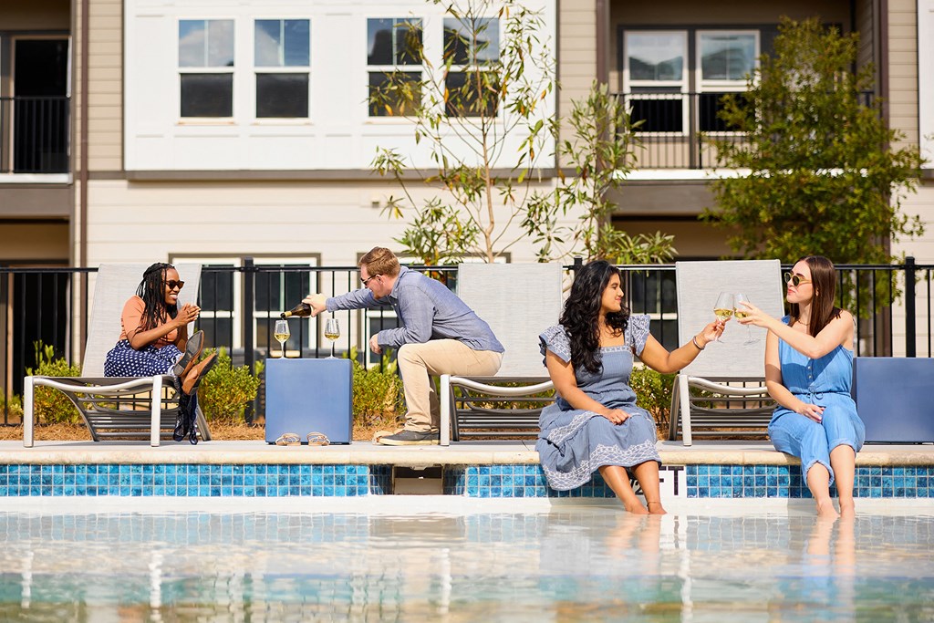 people sitting at the edge of a swimming pool with drinks