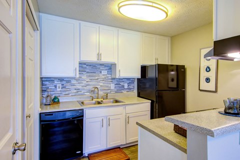 a kitchen with white cabinets and a black refrigerator