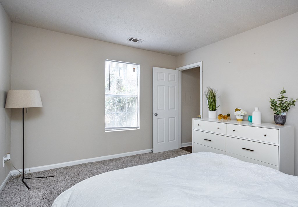 a bedroom with white cabinets and a white bed