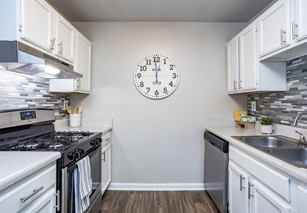 an open kitchen with stainless steel appliances and a large clock on the wall