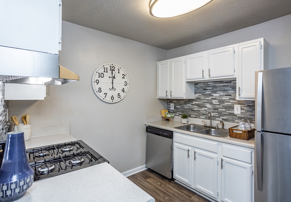 an open kitchen with a large clock on the wall and a stove and sink