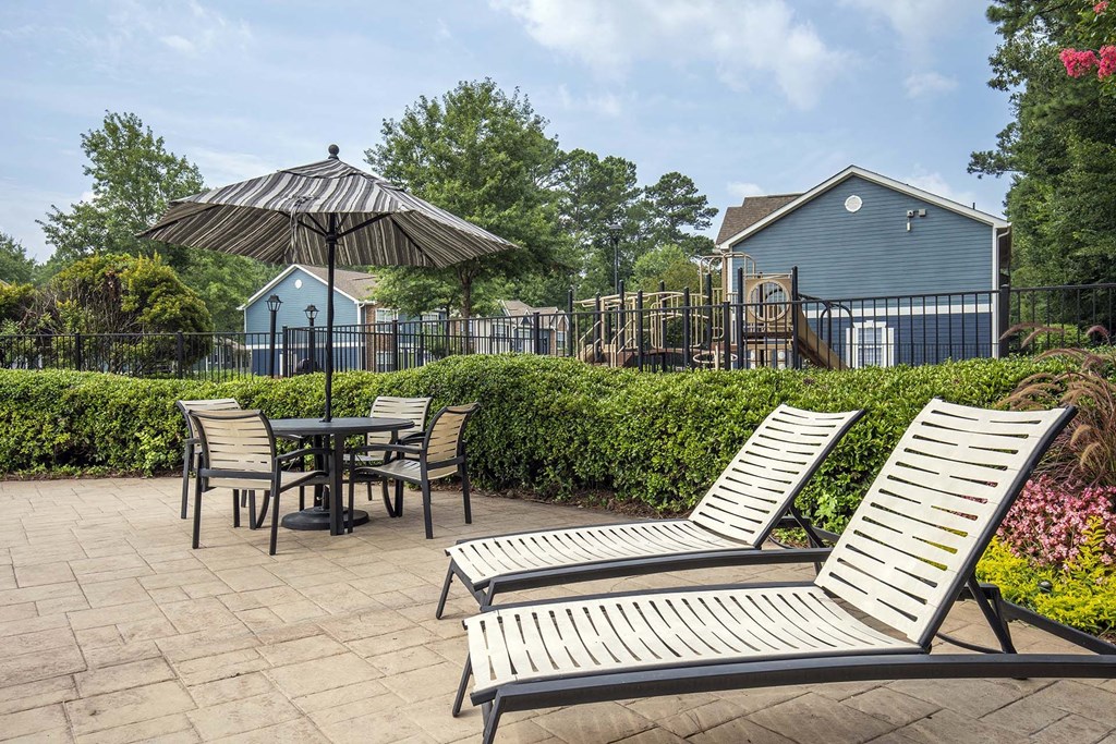 A patio with a table, chairs, and an umbrella.