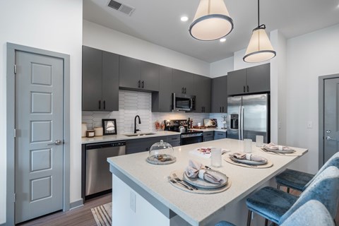 A modern kitchen with a dining table set for two.
