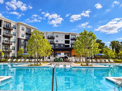 A large swimming pool in front of a multi-story apartment building.