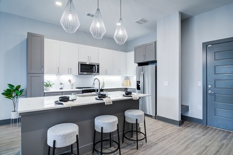 A modern kitchen with white cabinets and a grey island.