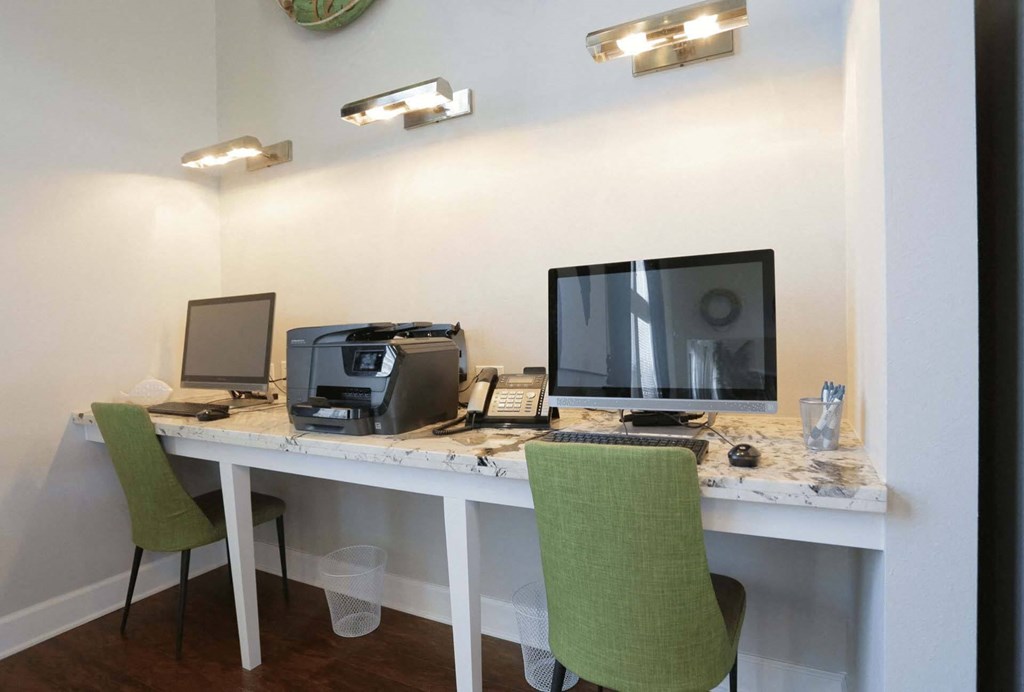 a desk with two computers and a printer on it
