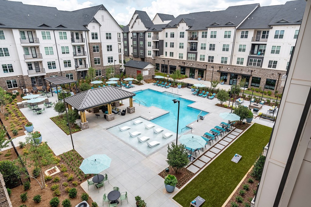 an aerial view of a resort style pool with lounge chairs and umbrellas