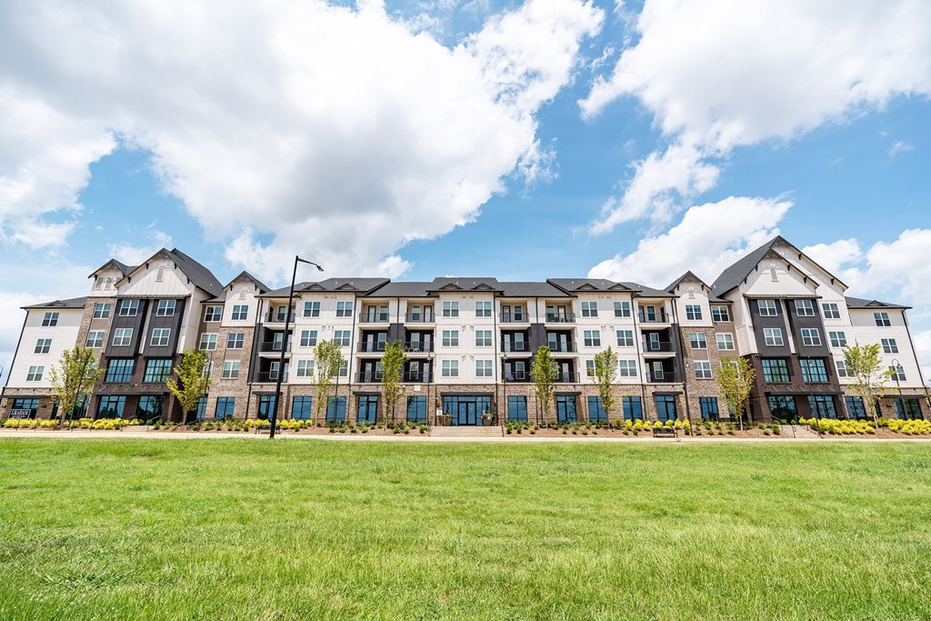 a large apartment building with a green lawn in front of it