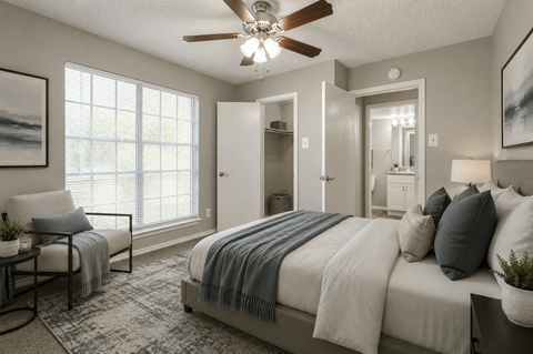 A bedroom with a bed, chair, and a ceiling fan.