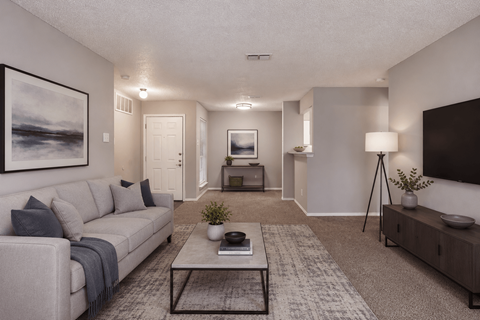 A living room with a grey couch, a coffee table, and a painting on the wall.