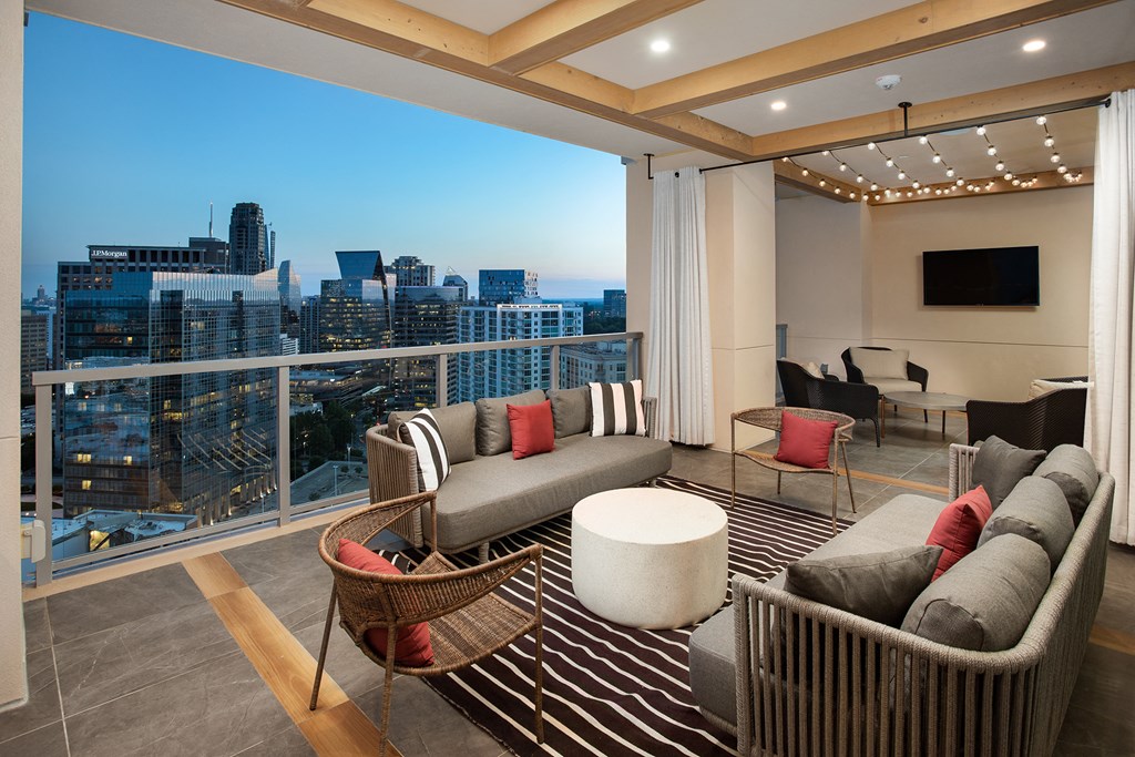 a living area with couches chairs and a rug with a view of the city