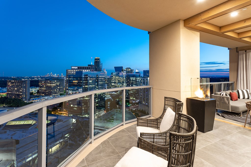 a balcony with two chairs and a table with a view of the city at night