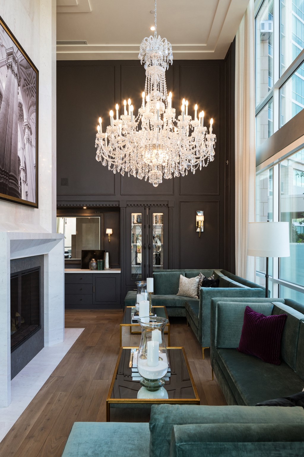 a large chandelier hangs above a large living room with green couches and a large