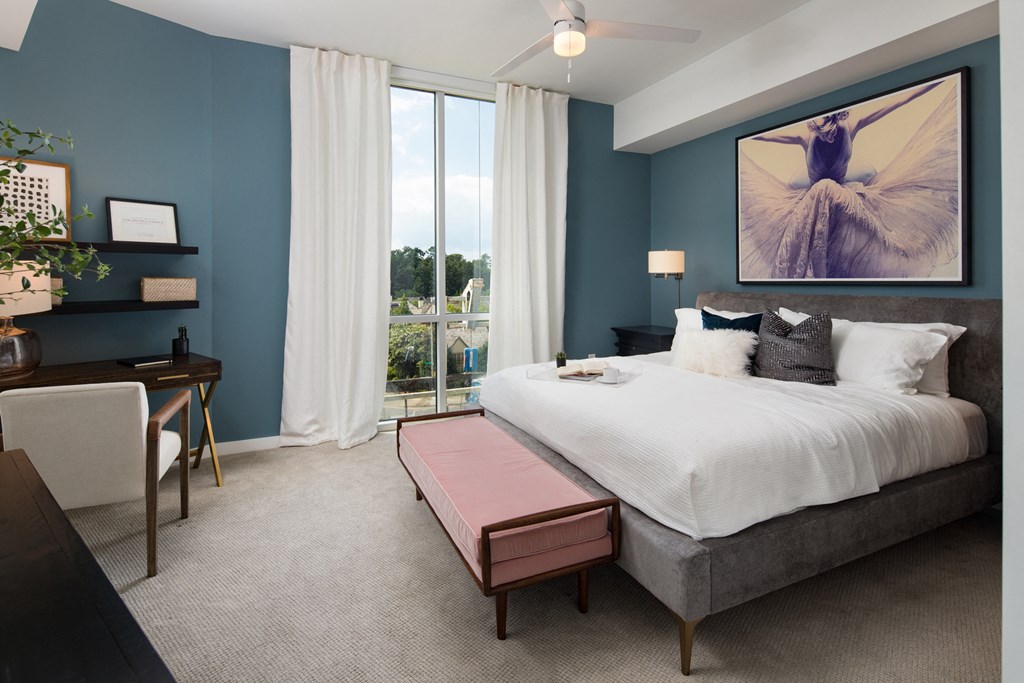 a bedroom with a bed and a desk with a chair in front of a window