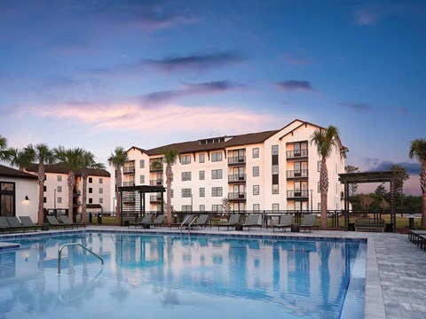 a swimming pool at dusk with an apartment building in the background