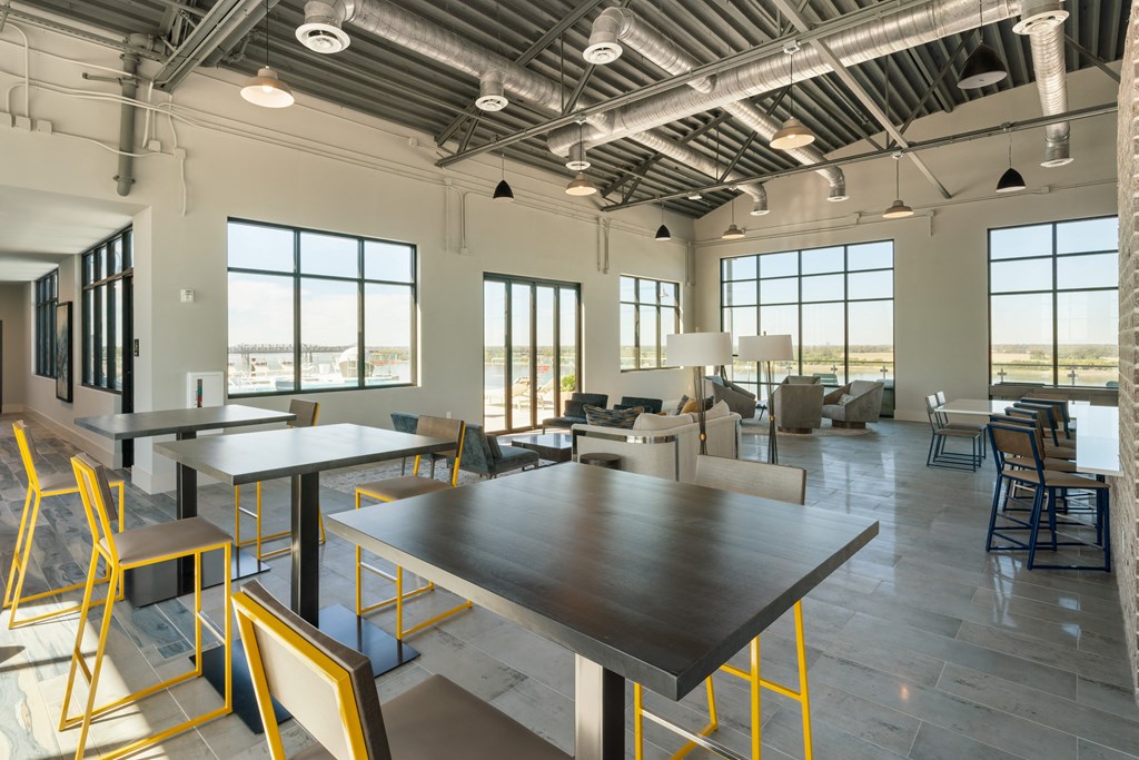 a large living room with tables and chairs and large windows