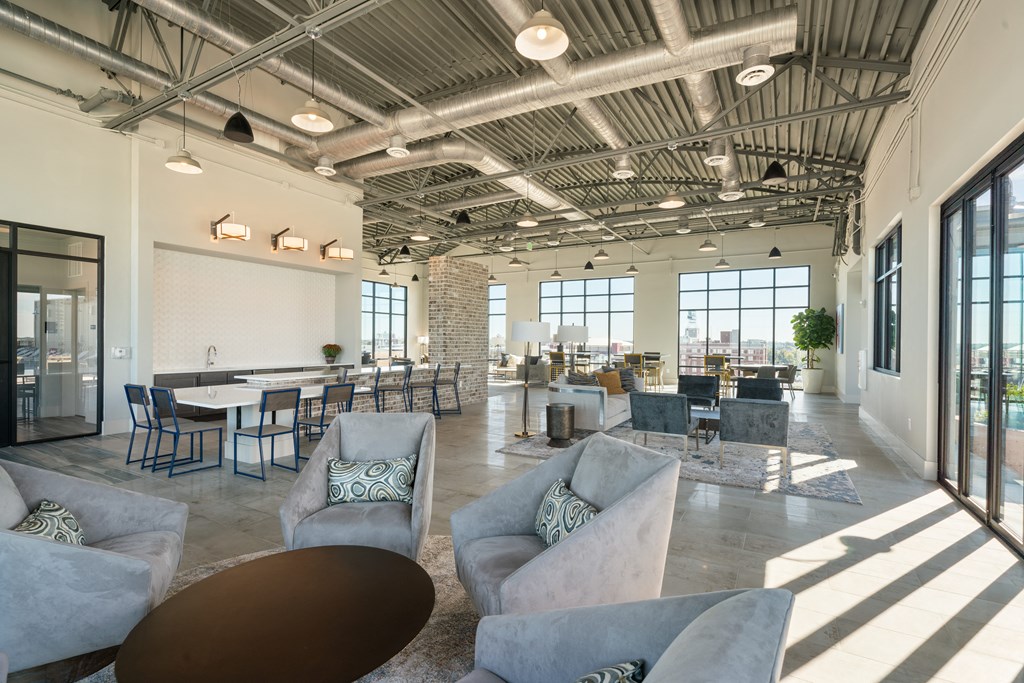 a living room with couches and chairs and tables in a building with large windows