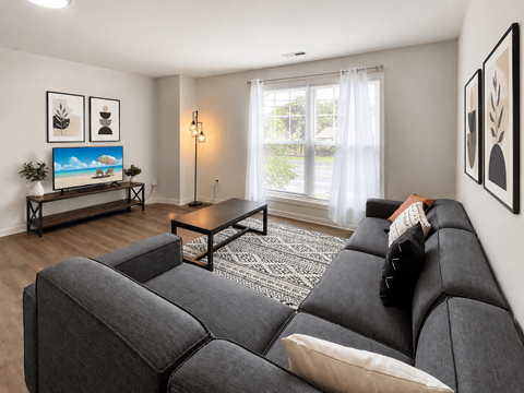 A living room with a grey couch and a painting on the wall.
