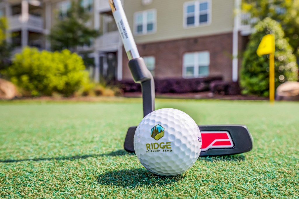 a golf ball and club on a tee in front of a house