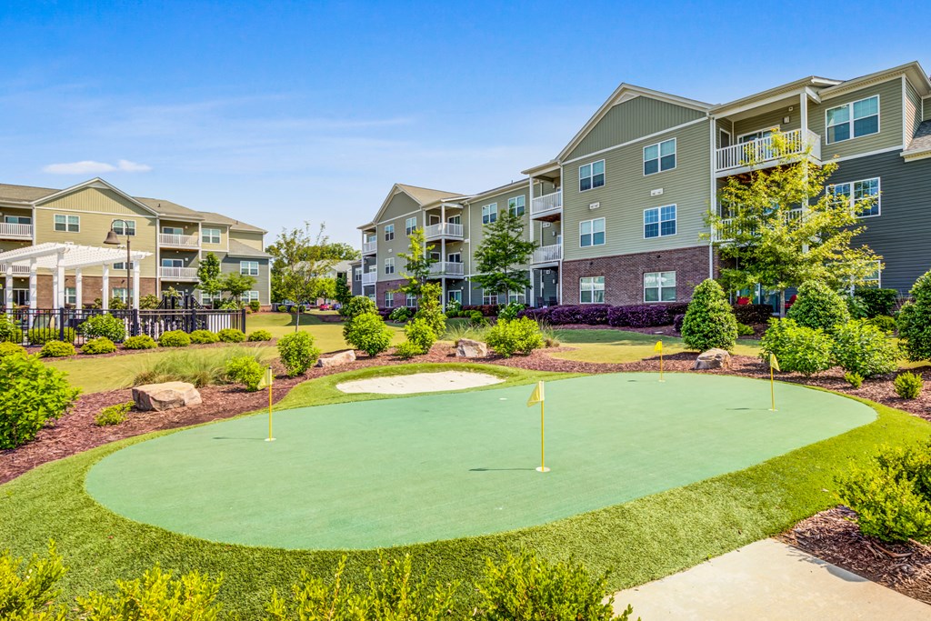 an outdoor putting green with an apartment building in the background