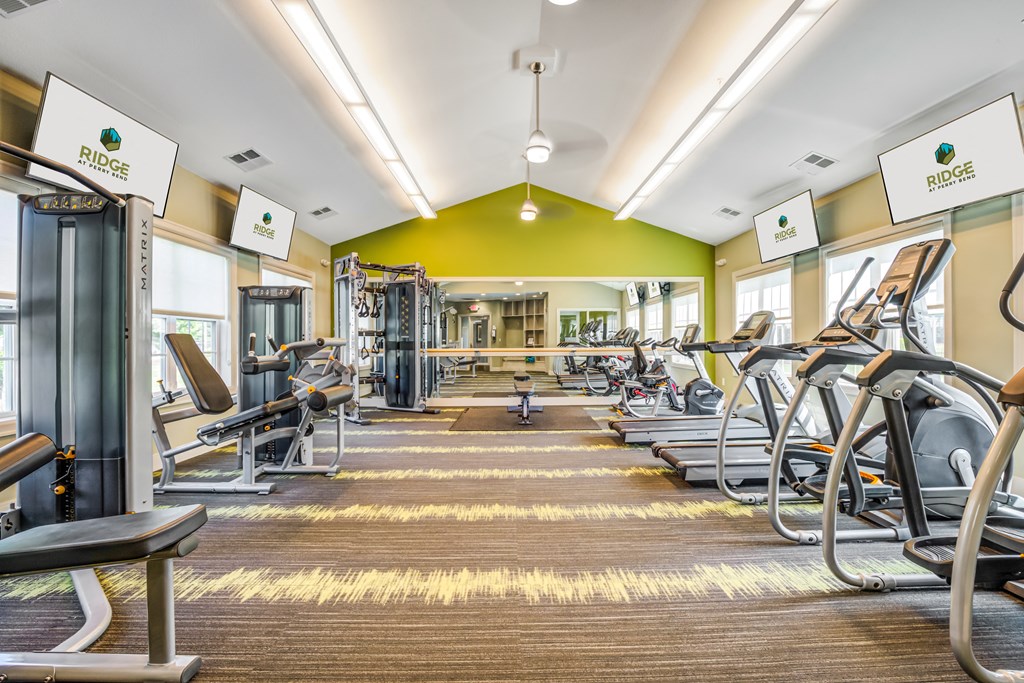 a gym with cardio equipment and weights on the floor