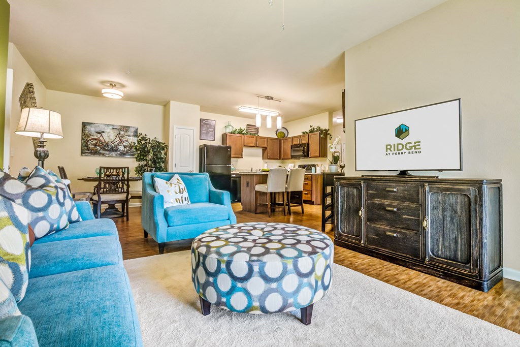 a living room with blue chairs and a ottoman in front of a couch