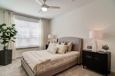 A bedroom with a large bed and a ceiling fan.