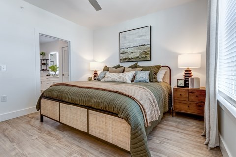 A bedroom with a bed, nightstand, and a painting on the wall.