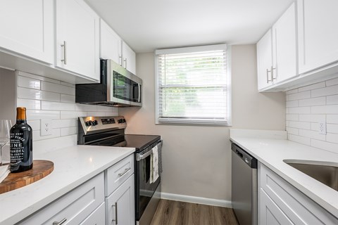 A kitchen with white cabinets and a black microwave.