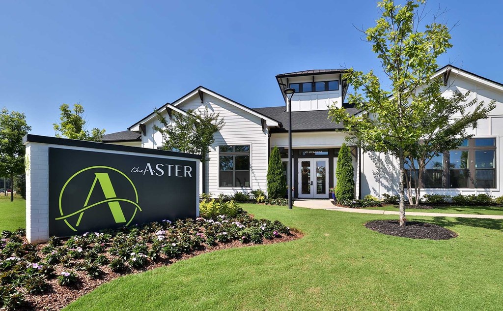 A white building with a green sign that says "Aster" in front of it.