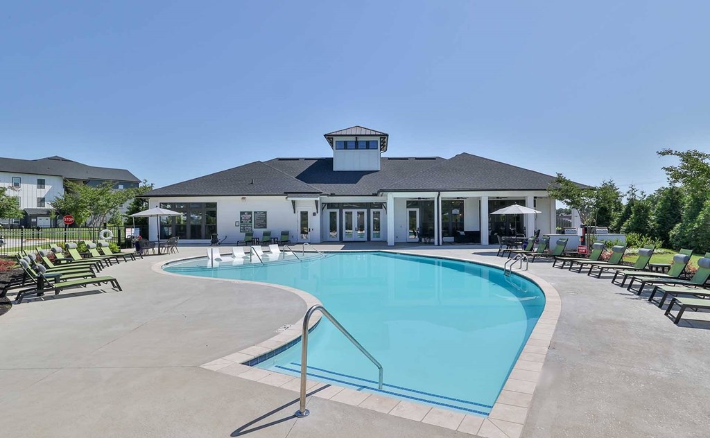 Apartments for Rent in Mauldin, SC - The Aster - An Outdoor Resort-Inspired Pool with Surrounding Lounge Seating in Front of The Resident Clubroom.