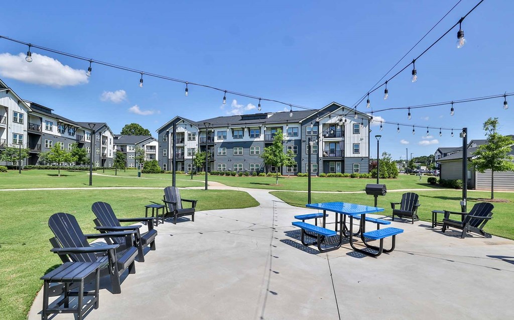 A sunny day at a park with picnic tables and chairs.