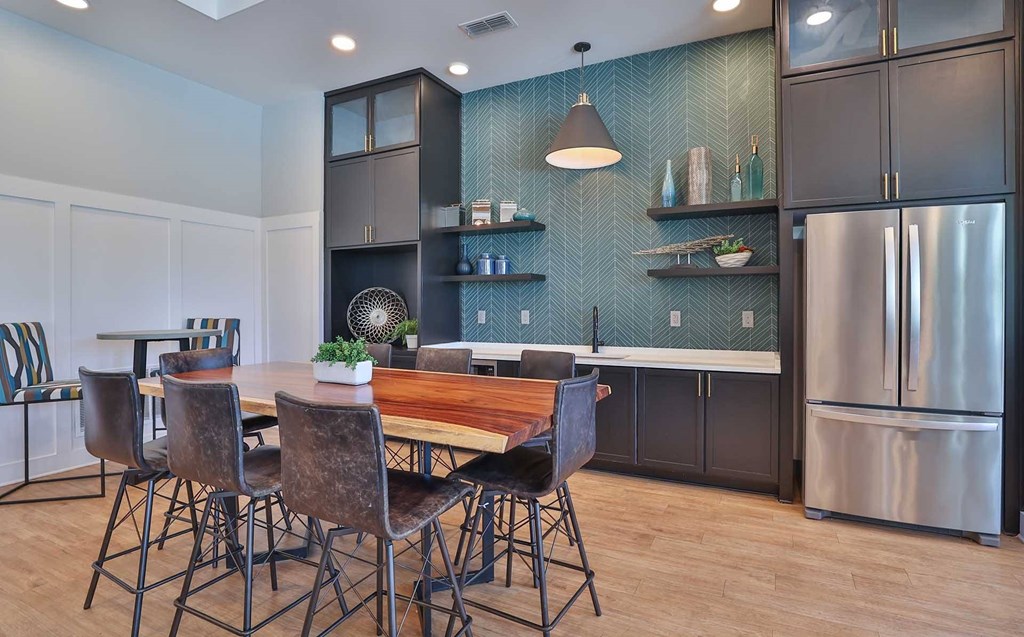 A kitchen with a table and chairs in the foreground and a refrigerator in the background.